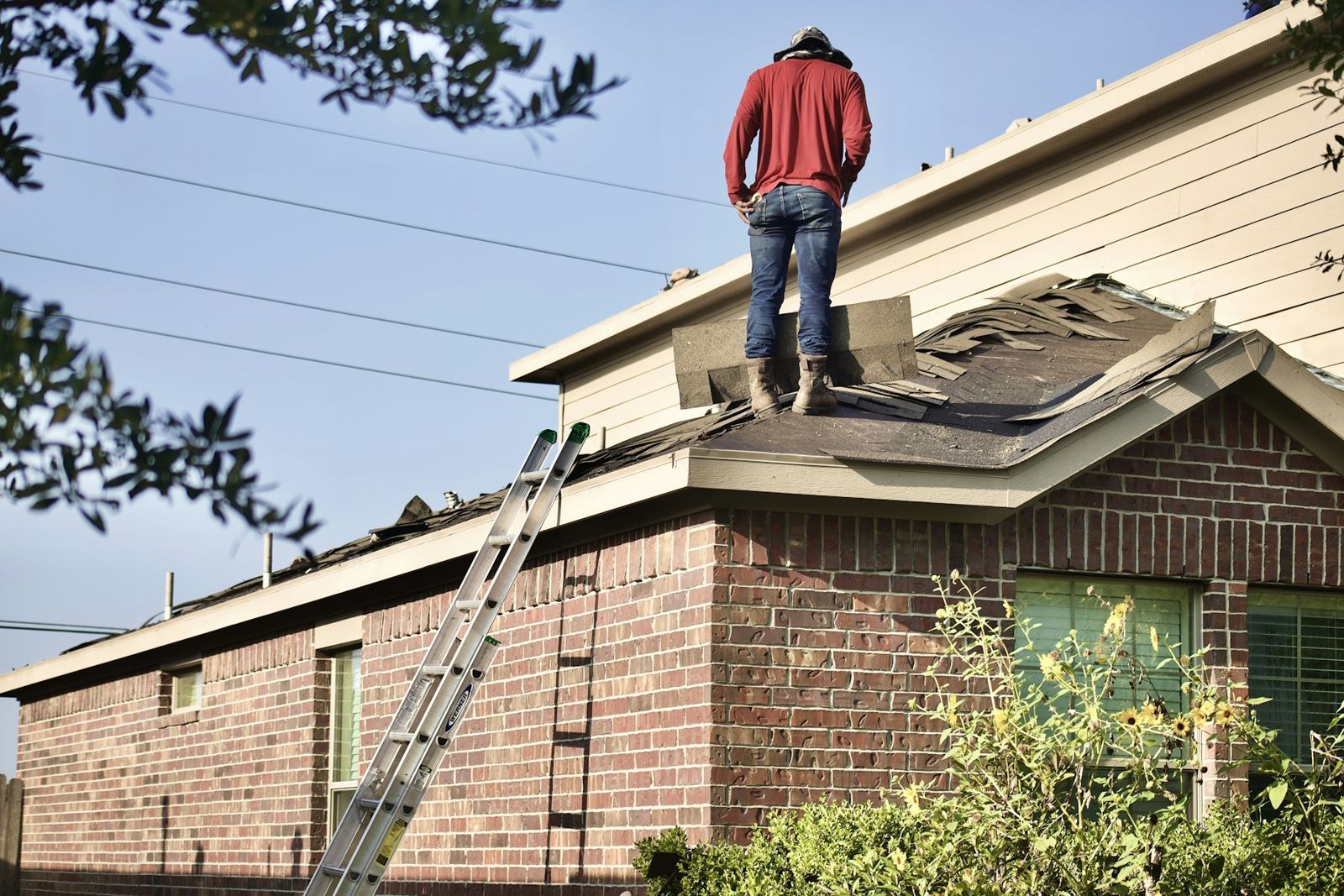 Roofer inspecting shingles on a brick home